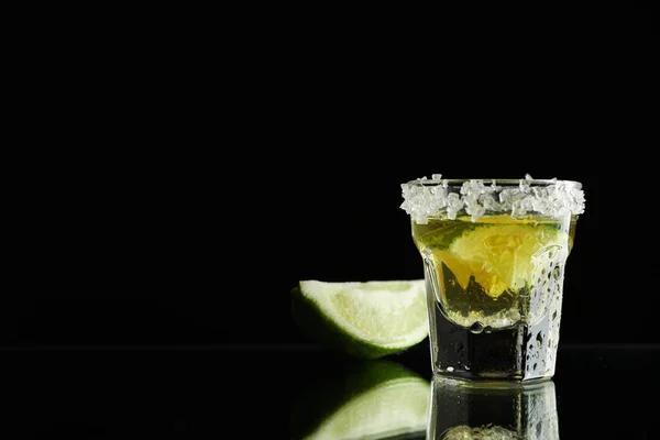 Tequila avec citron vert et sel de mer sur fond noir — Photo