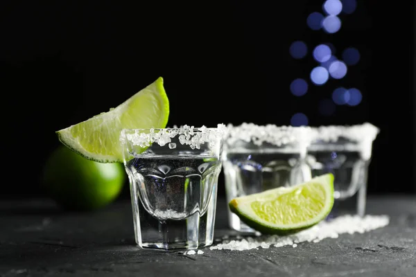 Colpi di tequila con fette di sale e lime su sfondo nero — Foto Stock