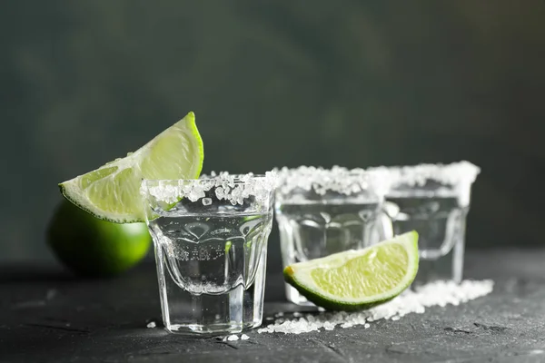 Tequila tiros com sal e fatias de limão no fundo preto — Fotografia de Stock