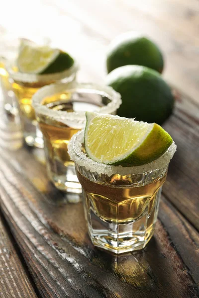 Tequila tiros com sal e fatias de limão na mesa de madeira, close-up — Fotografia de Stock