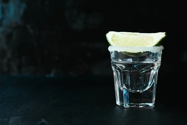 Tequila Shot mit Limette und Salz vor schwarzem Hintergrund mit Bl — Stockfoto