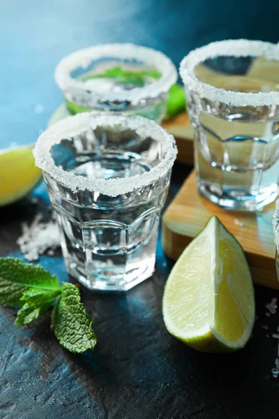 Tequila tiros com sal, fatias de limão e hortelã na mesa preta sagacidade — Fotografia de Stock