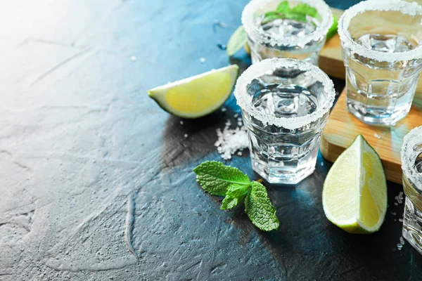 Tiros de tequila con sal, rodajas de lima y menta sobre mesa negra ingenio —  Fotos de Stock