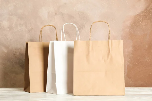 Papír táskák fehér tábla ellen, barna háttér, másolási tér — Stock Fotó