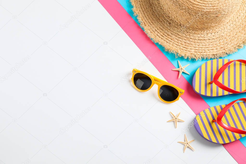 Flip flops, sunglasses, starfishes and straw hat on color backgr