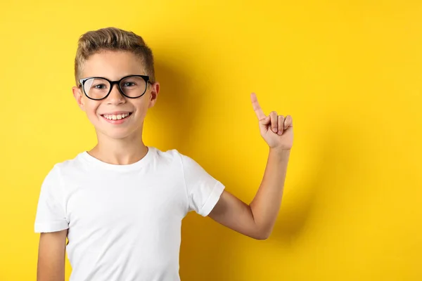 Garçon heureux dans des lunettes sur fond jaune, espace pour le texte — Photo