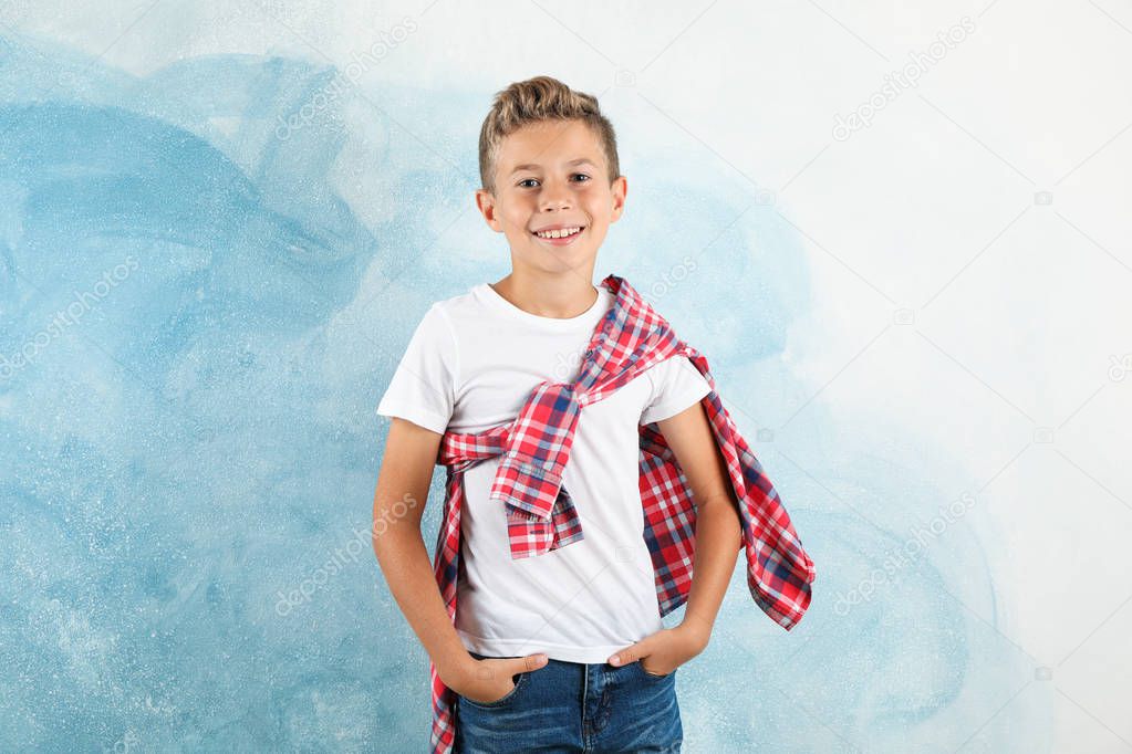 Boy in t-shirt, jeans and shirt against color background, space 