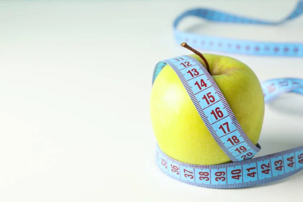 Manzana con cinta métrica sobre fondo blanco, primer plano — Foto de Stock