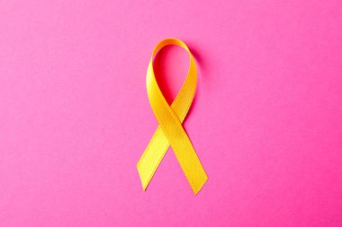 Pembe arkaplanda sarı farkındalık kurdelesi, metin için boşluk