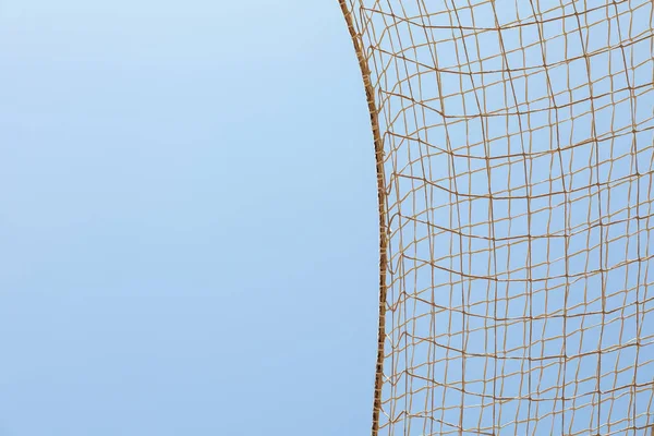 Football net against blue sky background, space for text