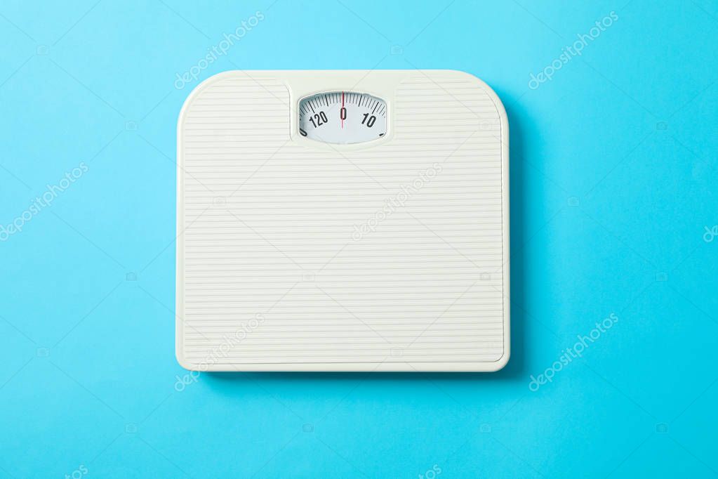White weigh scales on blue background, top view