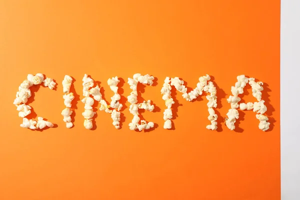 Слова кинотеатра выложены из попкорна на оранжевом фоне, копировать спа — стоковое фото