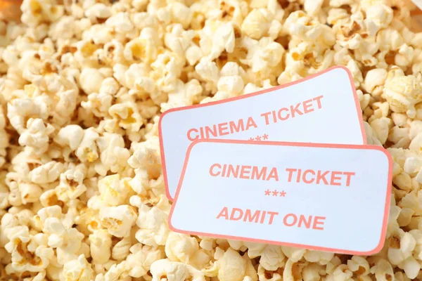 Cinema tickets on popcorn background, close up