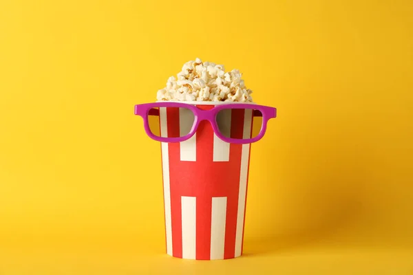 Striped bucket with popcorn and 3d glasses on yellow background, — Stock Photo, Image