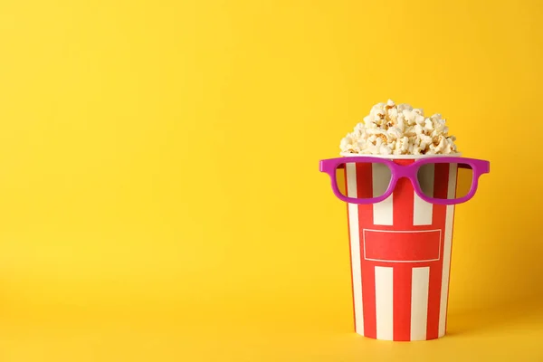 Striped bucket with popcorn and 3d glasses on yellow background, — Stock Photo, Image