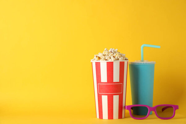 Bucket with popcorn, drink and 3d glasses on yellow background, 