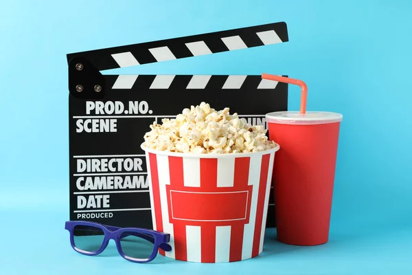 Clapperboard, bucket with popcorn, drink and 3d glasses on blue — Stock Photo, Image