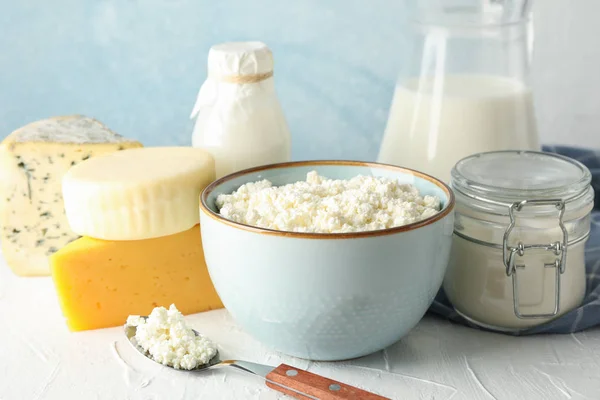 Diferentes produtos lácteos na mesa branca contra fundo azul — Fotografia de Stock