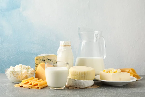 Produtos lácteos na mesa cinza contra fundo azul, espaço de cópia — Fotografia de Stock