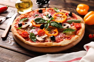 Lezzetli pizza ve ahşap arka plan üzerinde malzemeler, yakın