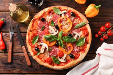 Ahşap arka planda lezzetli pizza ve malzemeler, üst görünüm