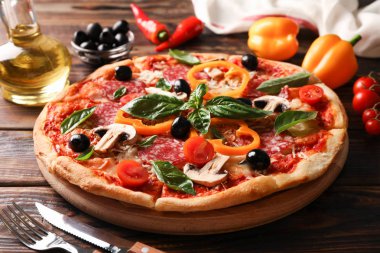Lezzetli pizza ve ahşap arka plan üzerinde malzemeler, yakın