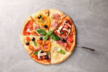Gri arka plan, alan üzerinde farklı parçalar ile lezzetli pizza 