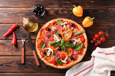 Ahşap arka planda lezzetli pizza ve malzemeler, üst görünüm