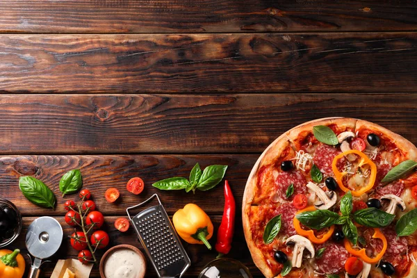 Ahşap arka plan üzerinde lezzetli pizza ve malzemeler, kopya alanı