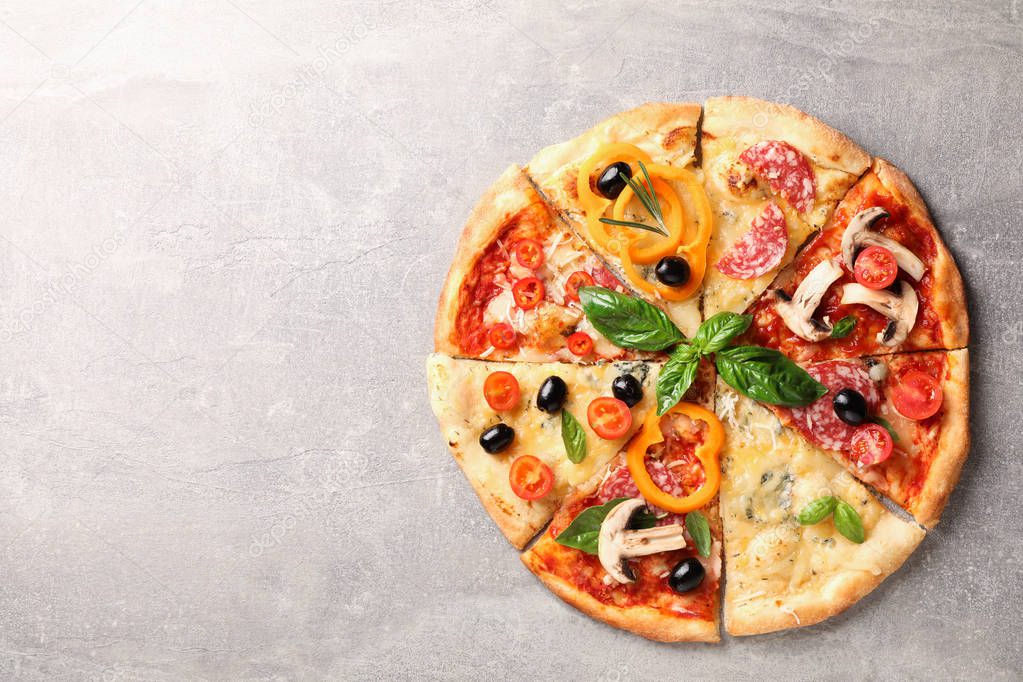 Delicious pizza with different pieces on grey background, space 