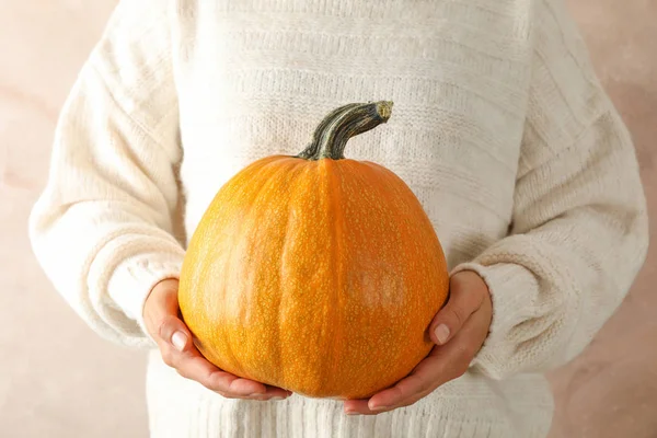 Kahverengi arka planda balkabağı tutan genç kadın, yakın