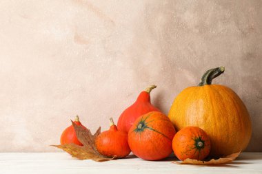 Composition with pumpkins and leaves on white wooden background,