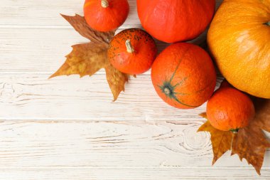 Composition with pumpkins and leaves on white wooden background,