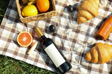 Composition with wine, croissants, fruits and towel on grass, to