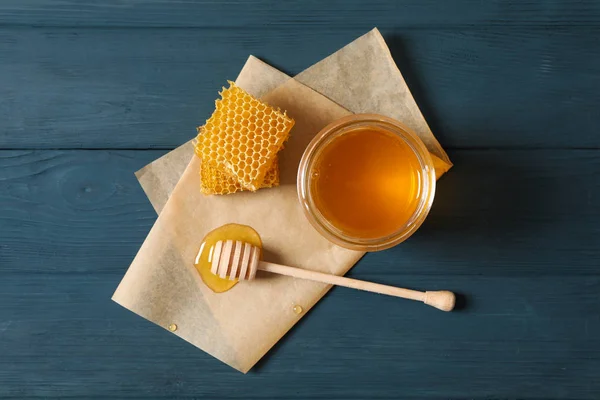 Tarro de vidrio con miel, cazo, panal y pergamino de madera — Foto de Stock