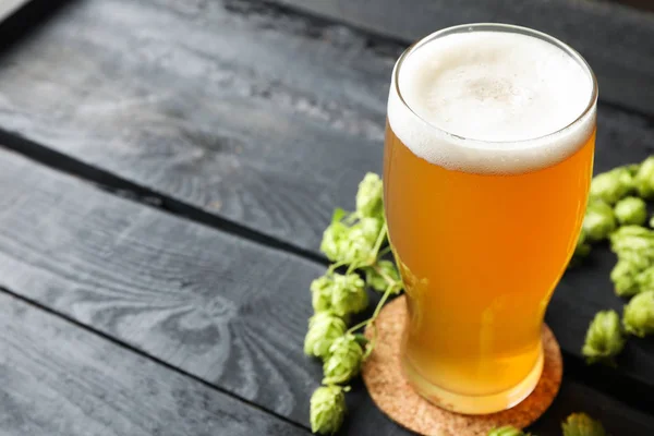 Verre de bière et cônes de houblon sur fond bois, espace de copie — Photo