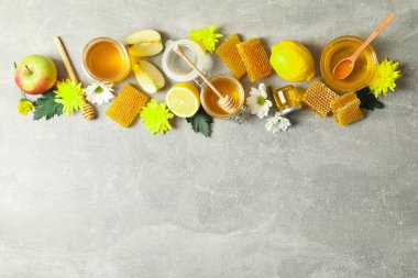 Düz gri arka plan üzerinde bal, çiçek ve meyve ile yatıyordu, kopya