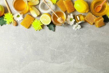 Düz gri arka plan üzerinde bal, çiçek ve meyve ile yatıyordu, kopya