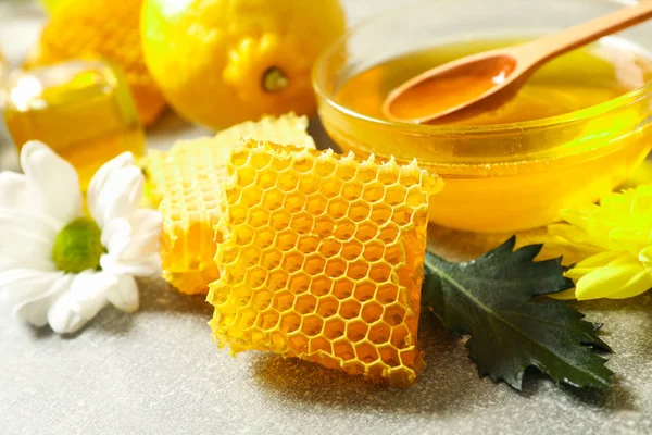 Honeycombs, cytryna i kwiaty na szarym tle, zbliżenie — Zdjęcie stockowe