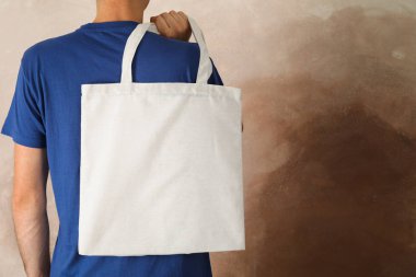 Genç adam kahverengi arka plan, boş alan karşı çanta tutan