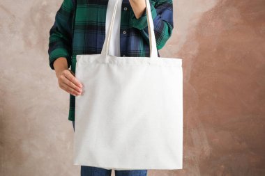 Genç kadın kahverengi arka plan, boş spa karşı çanta tutarak