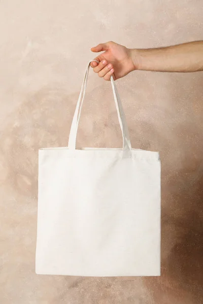 Male hand holding tote bag against brown background, empty space — Stock Photo, Image