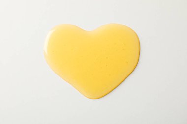 Beyaz arka planda kalp şeklinde bal birikintisi, üst görünüm