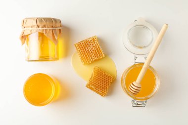 Düz yatıyordu. Beyaz backgro üzerinde bal, dipper ve petek ile Kavanoz