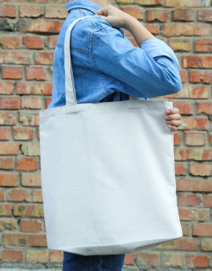 Genç kadın tuğla duvara karşı çanta tutan, boş alan