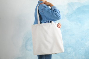 Mavi arka plan, boş boşluk karşı çanta tutan genç kadın