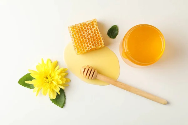 Nido de abeja, cazo, tarro con miel y flor sobre fondo blanco — Foto de Stock