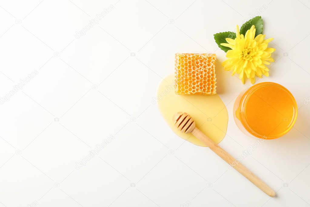 Honeycomb, dipper, jar with honey and flower on white background