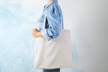 Mavi arka plan, boş boşluk karşı çanta tutan genç kadın