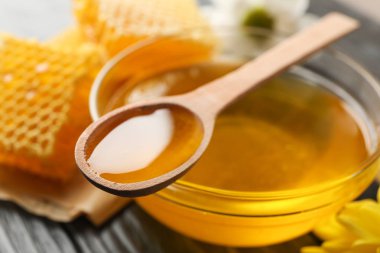 Ahşap arka plan üzerinde çiçek, bal ve dipper ile cam kase, 